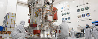 Engineers and technicians work on the towering main body of NASA’s Europa Clipper spacecraft at the agency’s Jet Propulsion Laboratory. 