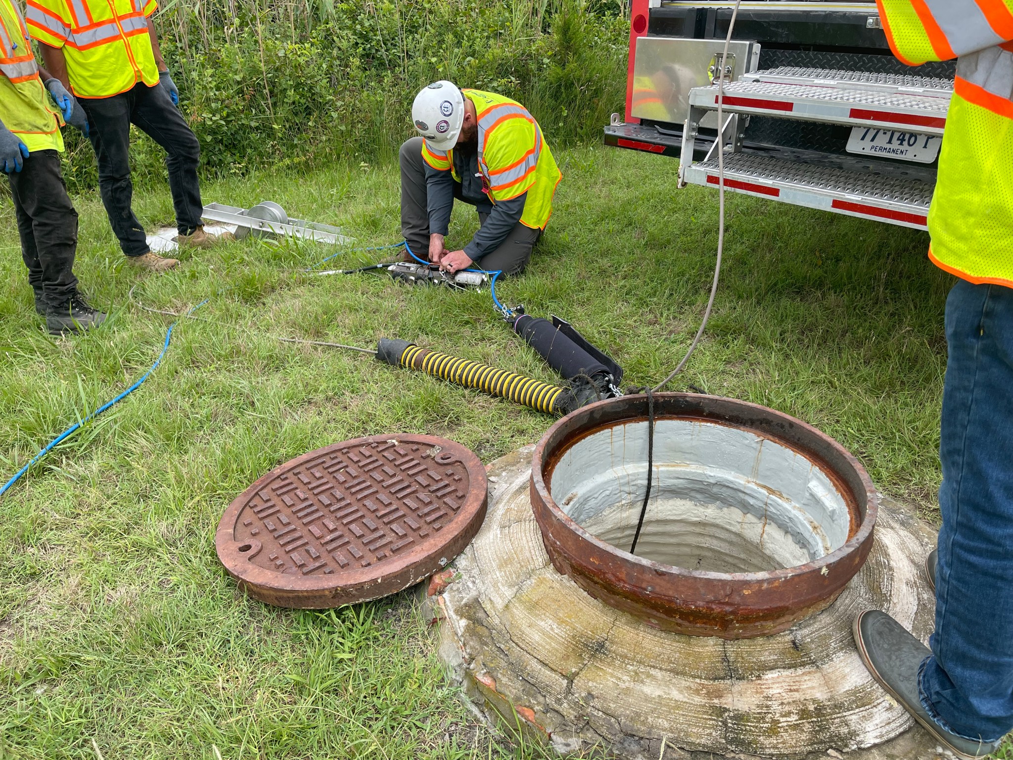 Technicians in bright yellow vests and hard hats work around an open