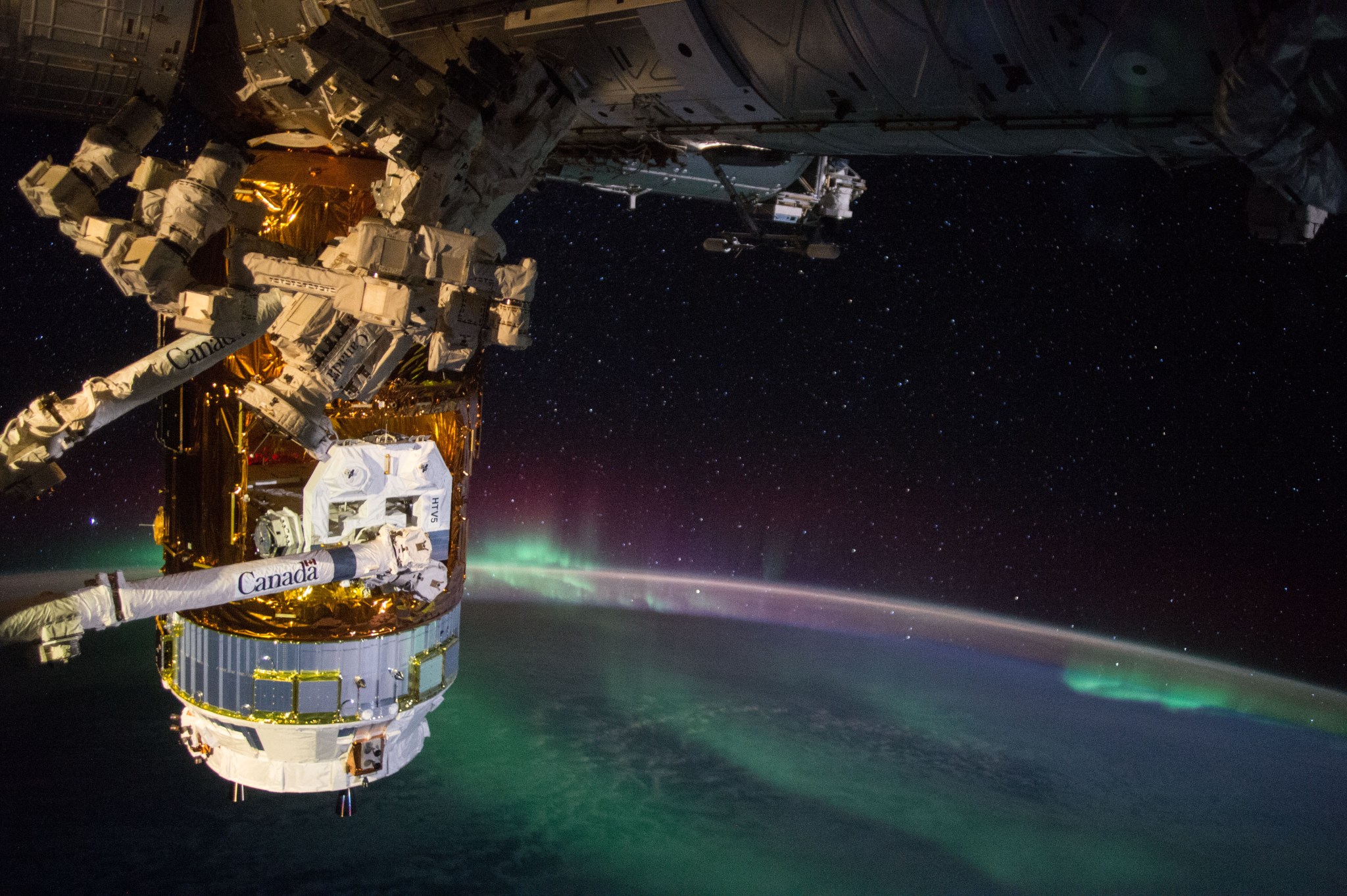 The Japan Aerospace Exploration Agency (JAXA) Kounotori 5 H-II Transfer Vehicle (HTV-5) is seen berthed to the International Space Station. The external CALET experiment, which will search for signatures of dark matter, is seen being extracted from the unpressurized section by the station's robotic arm, Canadarm2. The unpiloted cargo craft, named "Kounotori," which is Japanese for "white stork," is loaded with more than four-and-a-half tons of research and supplies, including water, spare parts and experiment hardware.
