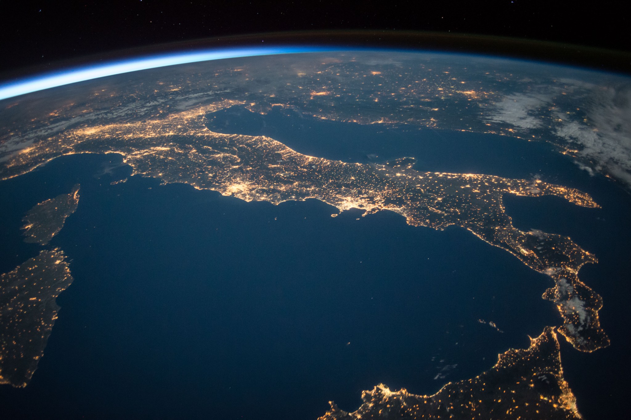 The familiar u0022bootu0022 shape of the country of Italy stands out in this nighttime image with sparkling city lights reaching from Sicily off the u0022toeu0022 of the boot, to the approaches to the Alps on the north end of the country.