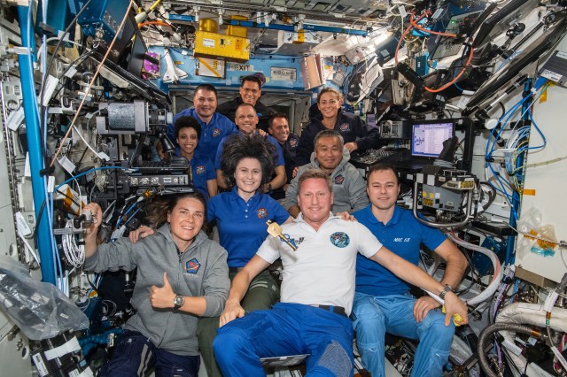 The eleven Expedition 68 crew members aboard the International Space Station pose for a portrait. In the front row from left, are cosmonauts Anna Kikina, Sergey Prokopyev, and Dmitri Petelin. In the next row, are astronauts Samantha Cristoforetti of ESA (European Space Agency) and Koichi Wakata of the Japan Aerospace Exploration Agency (JAXA). In the back, are NASA astronauts Jessica Watkins, Kjell Lindgren, Bob Hines, Frank Rubio, Josh Cassada, and Nicole Mann. A symbolic key, representing the traditional change of command ceremony, that Cristoforetti earlier handed over to Prokopyev floats in the center of the frame as he begins his spaceflight as Expedition 68 Commander.