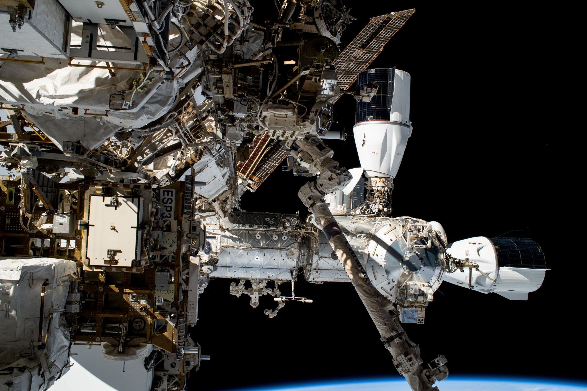 Two SpaceX Dragon vehicles are pictured docked to the International Space Station's Harmony module in this photograph taken from NASA astronaut Woody Hoburg's camera during a six-hour and three-minute spacewalk. At top, is the Dragon cargo vehicle that docked to Harmony's space-facing port on June 6 with over 7,000 pounds of science experiments, crew supplies, and station hardware. At right, is the Dragon crew vehicle that docked to Harmony's forward port on March 3 carrying four SpaceX Crew-6 crew members.