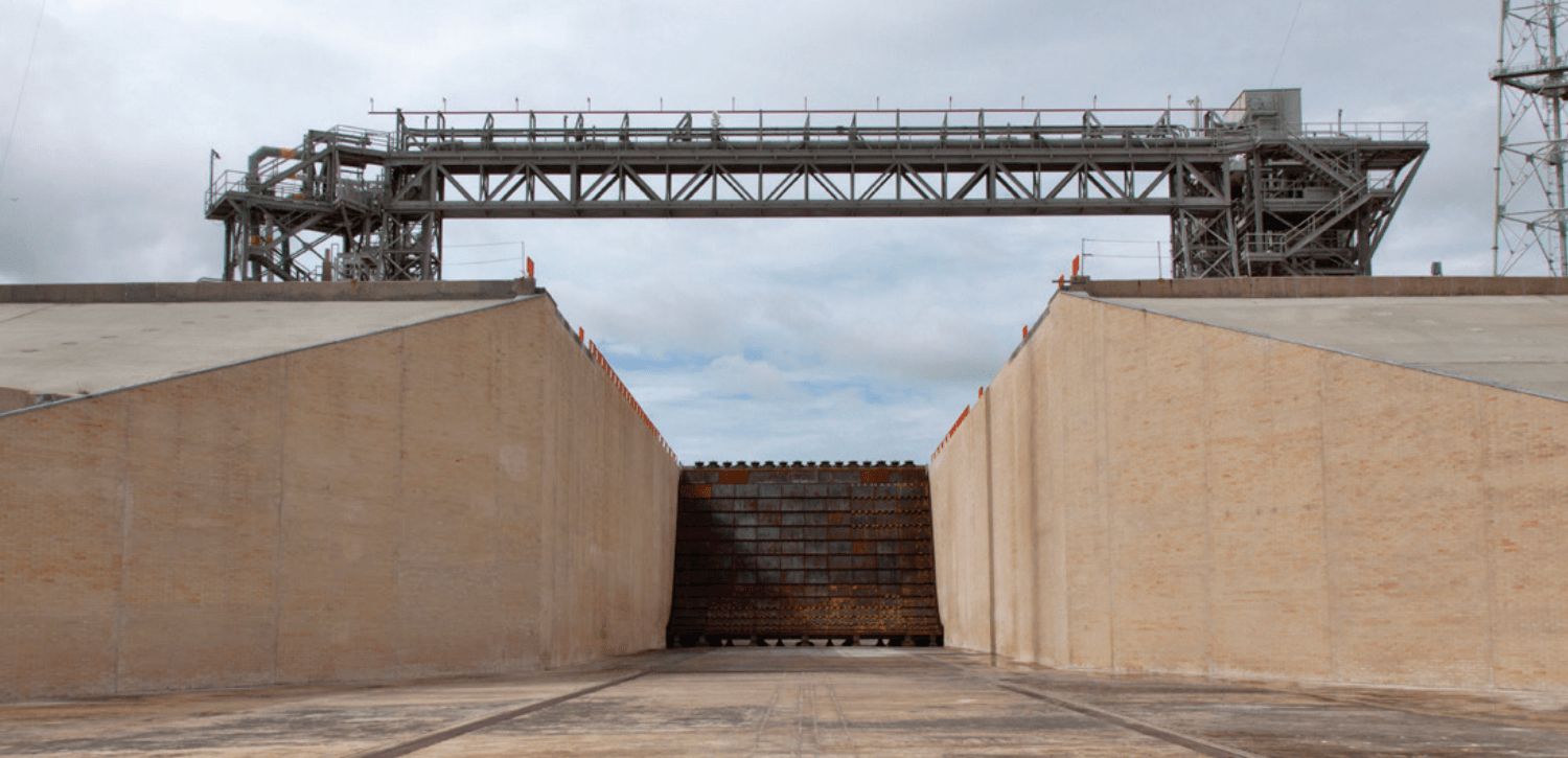 Two concrete sides with a large metal bridge over the two sides and a rusty metal insert in between the two sides