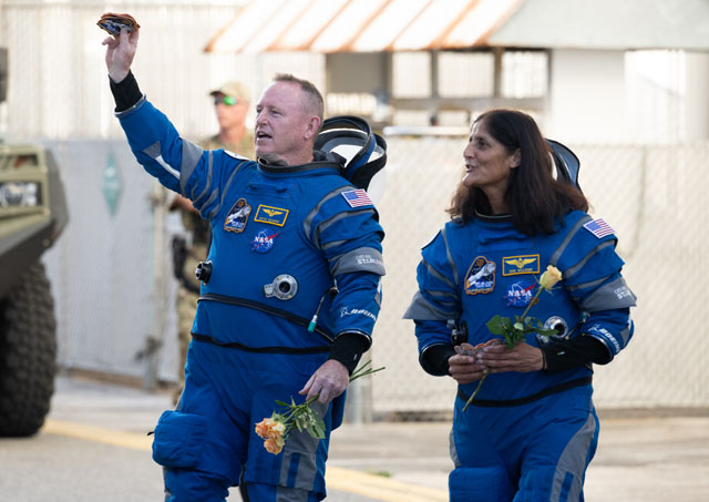 Astronauts Butch Wilmore and Suni Williams wave to the crowd prior to launch of the Boeing Starliner while in their blue spacesuits.