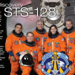 Portion of the STS-128 crew poster showing seven astronauts in orange flight suits with text to the side about the crew and the shuttle in orbit behind them