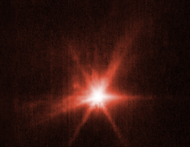 View of Didymos-Dimorphos asteroid system after DART impact. Webb's view, hued in red, shows a bright center and darker streaks emanating outward from it.