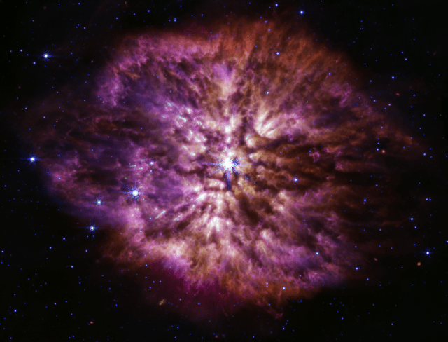 A large, bright star shines from the center with smaller stars scattered throughout the image. A clumpy cloud of material surrounds the central star, with more material above and below than on the sides.