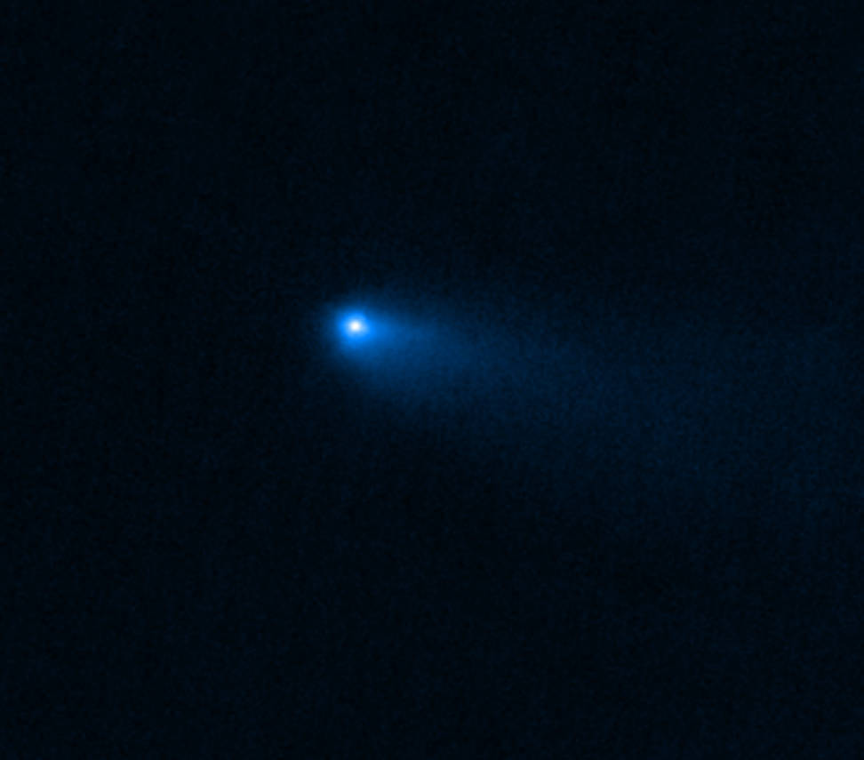 In the center of a black image, a small glowing, hazy point glows white, surrounded by blue that trails off to the lower right.