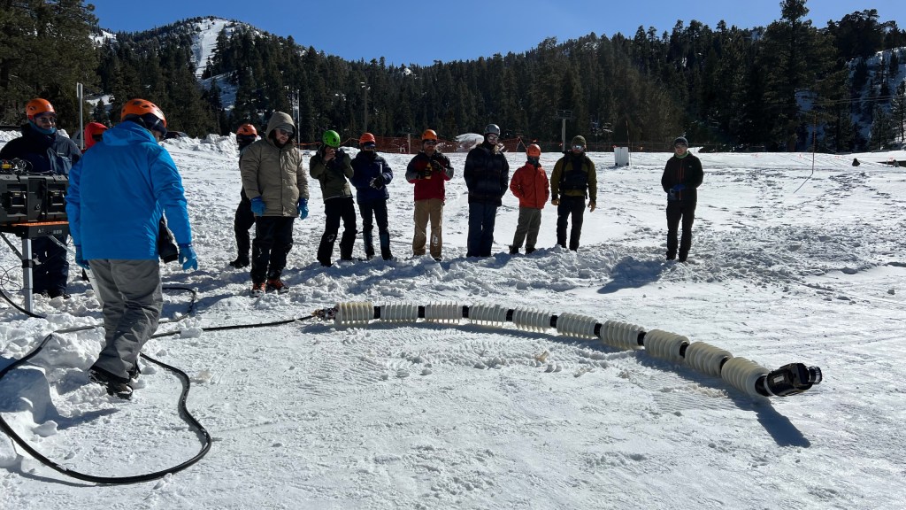 JPLers test a snake robot called EELS. Designed to sense its environment, calculate risk, travel, and gather data without real-time human input, EELS could eventually explore destinations throughout the solar system.
