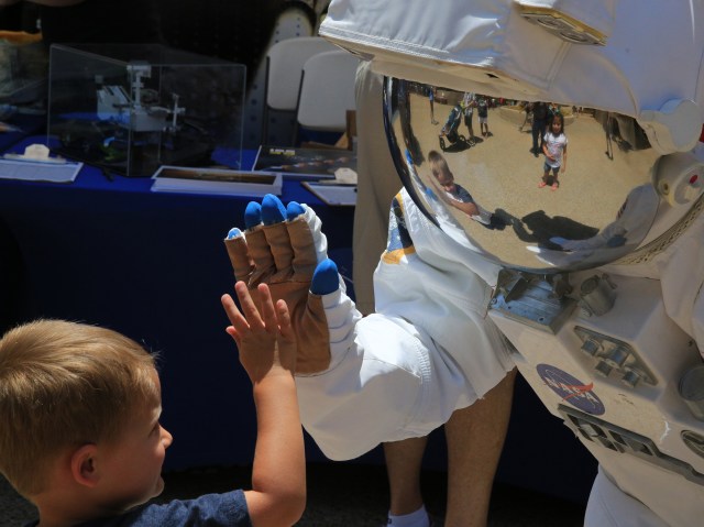 A NASA Langley Research Center employee in a space suit shares their knowledge with and gives a high-five to a guest at Busch Gardens in Williamsburg, Virginia.