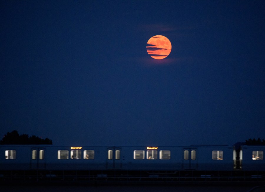 The Moon rises as a Metrorail car crosses the Potomac river in Washington