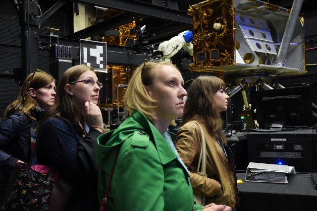 A group of people looks are equipment during a tour at Goddard.