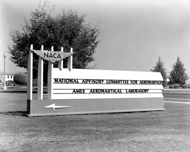 Black and white photo of the original Ames welcome sign, with the NACA insignia, National Advisory Committee for Aeronautics, Ames Aeronautical Laboratory.