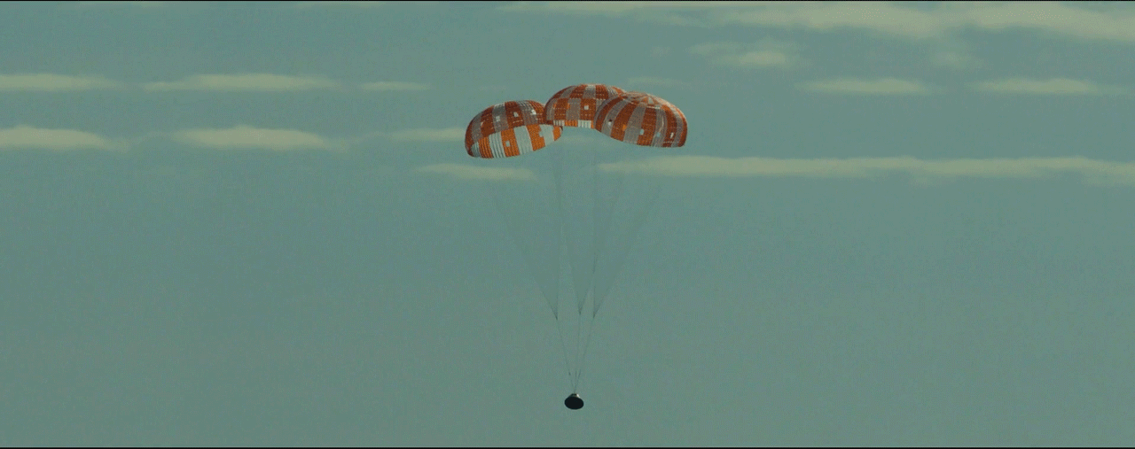 Animated gif showing the Orion spacecraft descending toward the Pacific Ocean, with parachutes trailing above it.