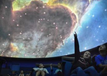 A child pointing at the ceiling inside a planetarium