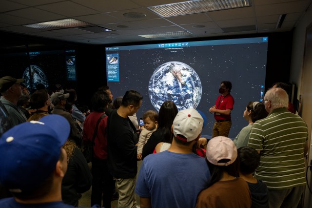 An employee uses the JPL-developed Eyes on Earth data visualization application to demonstrate to visitors how we study the changing Earth.