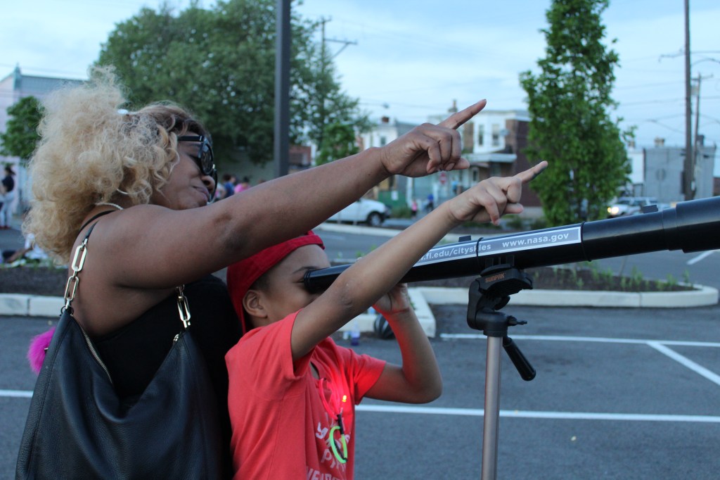 An adult and child look through a telescope together