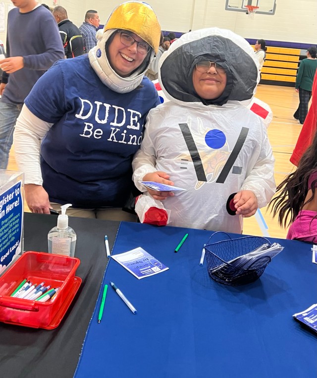 Photo of two educators wearing astronaut costumes while smiling and posing for a picture
