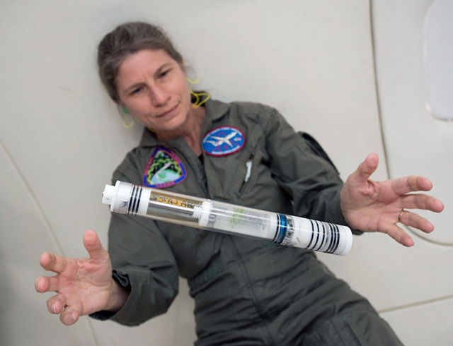 A Kennedy Space Center Fixation Tube floats in microgravity with researcher in background during a parabolic flight.