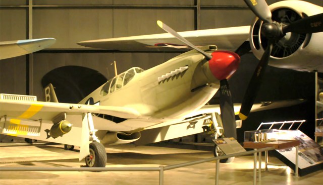 If These Airplanes Could Talk cover with an airplane inside a museum. It has a red nose with propellers and yellow stripes on the underside of the wing.