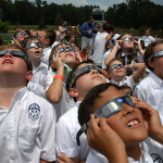 A group of students looking at the Sun wearing protective glasses