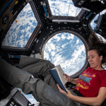 NASA astronaut Megan McArthur reads a book in the cupola