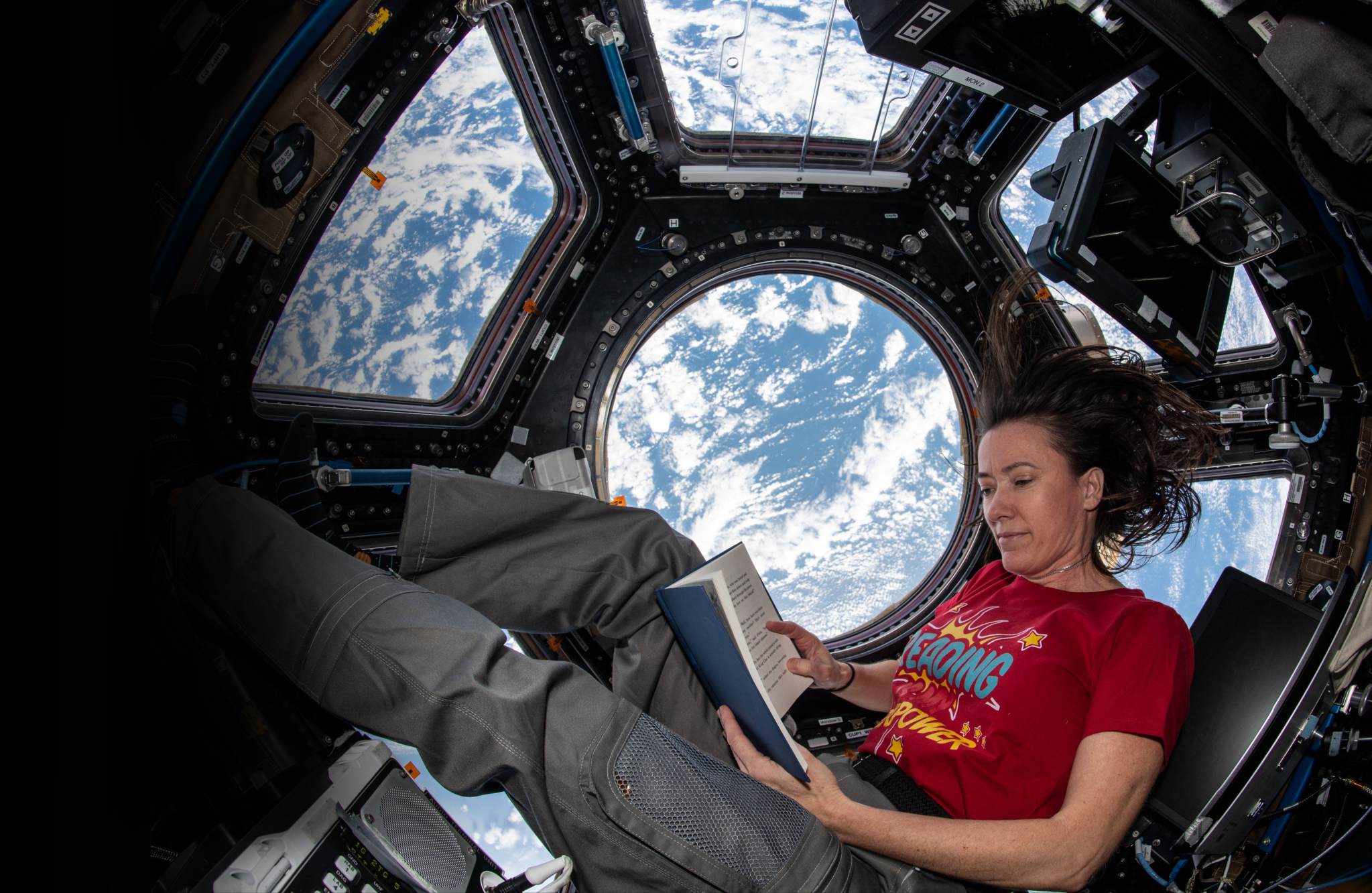 NASA astronaut Megan McArthur reads a book in the cupola