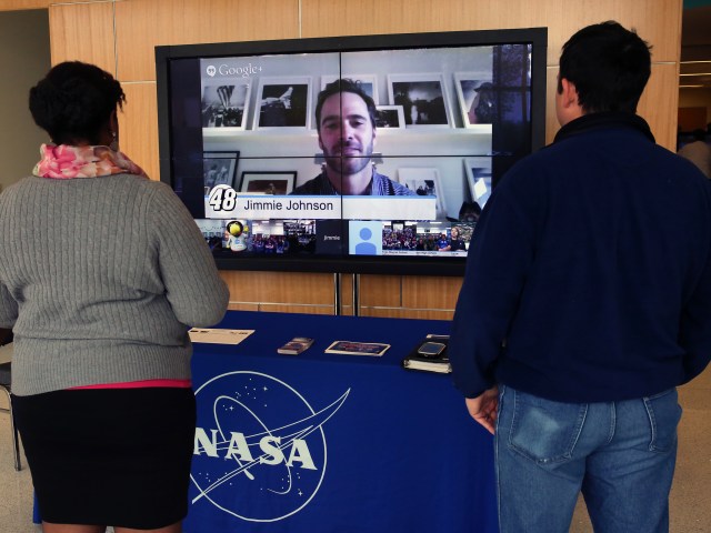 Visitors at NASA Langley watch a TV screen as NASCAR driver Jimme Johnson connected virtually with students, educators, and Langley subject matter experts for the online event "The Force of Drag: Bad for Cars, Good for Mars."
