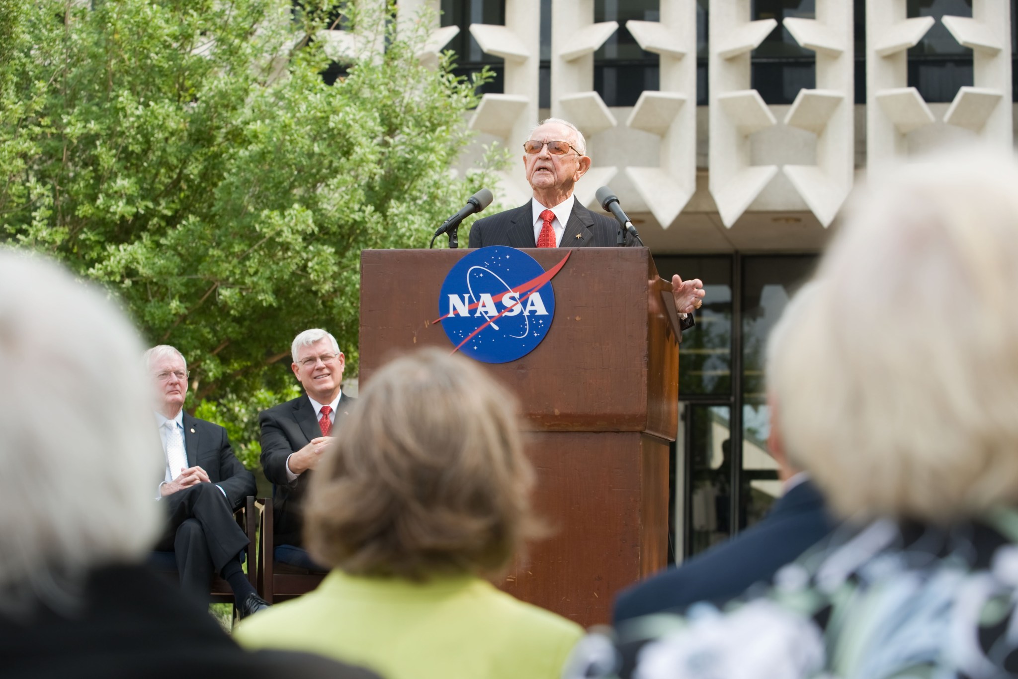 Former Center Director, Chris Kraft, at a podium in front of the newly dedicated Christopher C. Kraft, Jr. Mission Control Center (Bldg. 30) at Johnson Space Center in Houston.