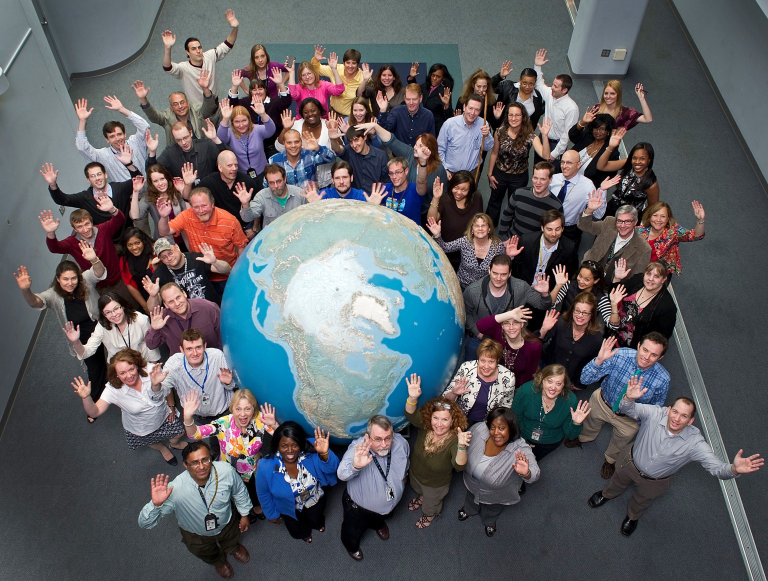 group photo of JSC employees around earth sculpture