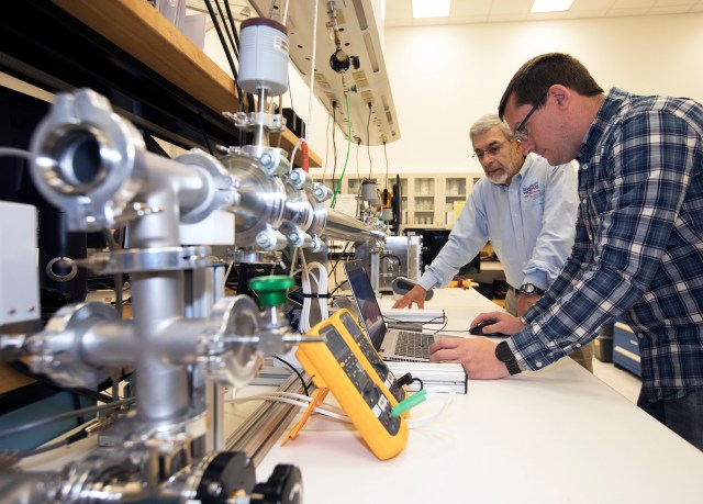 Two scientists modify an electrostatic precipitator at NASA's Kennedy Space Center in Florida.