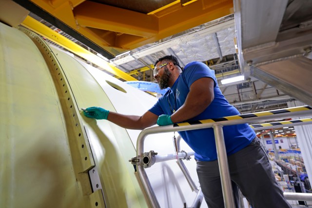 A technician works on part of the Space Launch System (SLS) rocket’s core stage for Artemis II in this March 11, 2023, image. Artemis II is the first Artemis mission that will send four astronauts around the Moon and return them home.