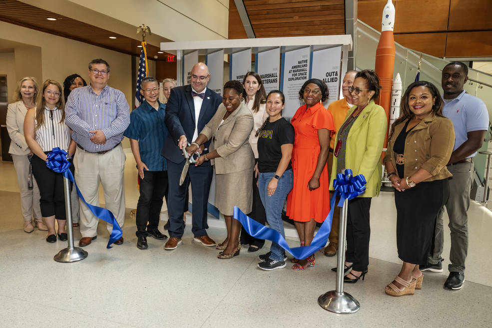 Tora Henry, center, and Joseph Pelfrey, left of center, cut the ribbon June 20 on a new display highlighting the centers many employee resource groups (ERGs).