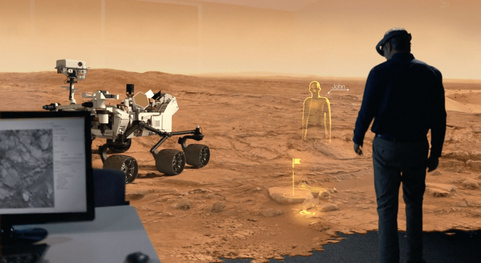 Person wearing virutal reality goggles and looking around on Mars with rover near them.