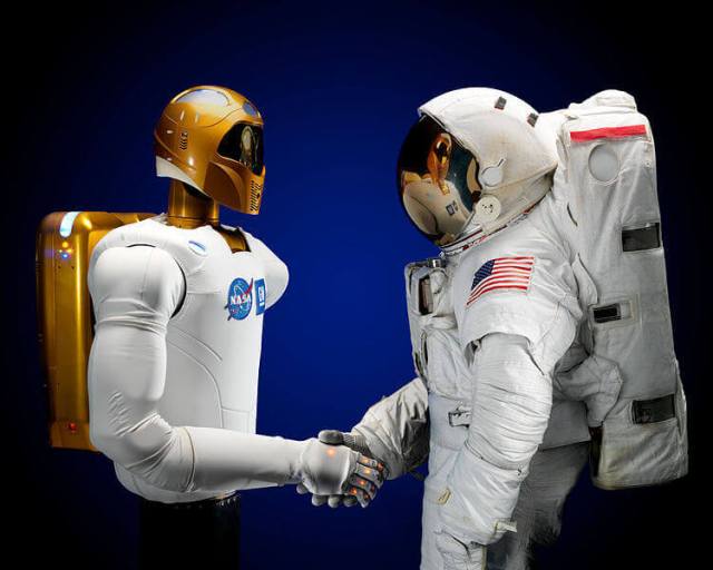 A robot and astronaut shake hands.