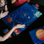 3 people playing a board game that was developed to accompany a planetarium show
