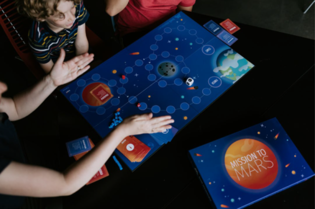 3 people playing a board game that was developed to accompany a planetarium show