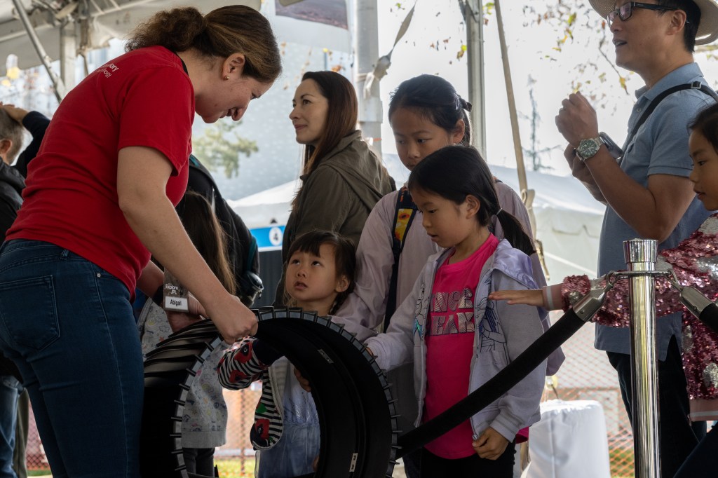 A JPLer shows the Mars Perseverance rover wheel design at the 2023 Explore JPL public event.