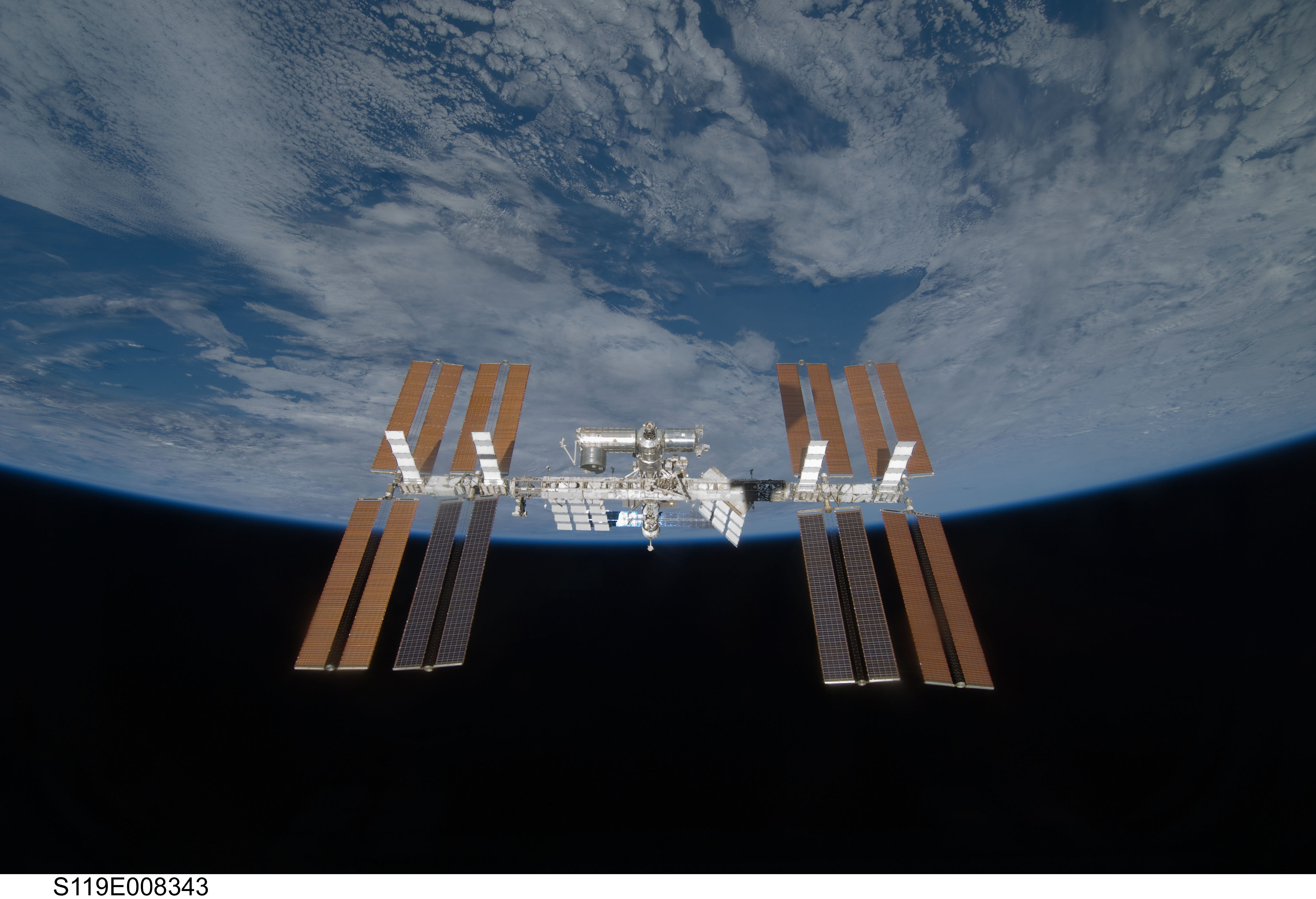 Backdropped by the blackness of space and Earth's horizon, the International Space Station is seen from Space Shuttle Discovery as the two spacecra...