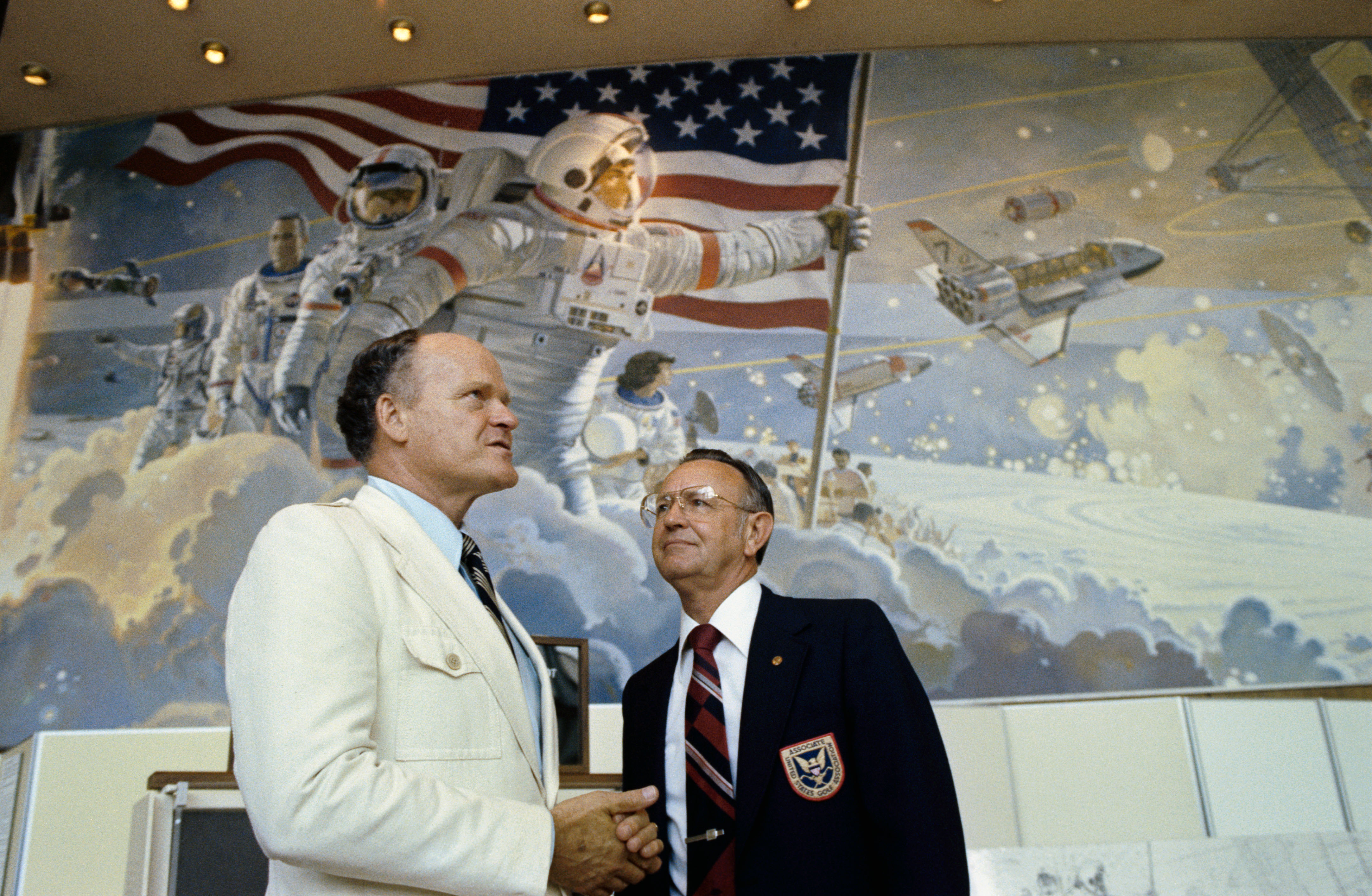 Robert T. McCall and Chris Kraft standing in front of the mural in JSC's Visitor Center (Building 2).