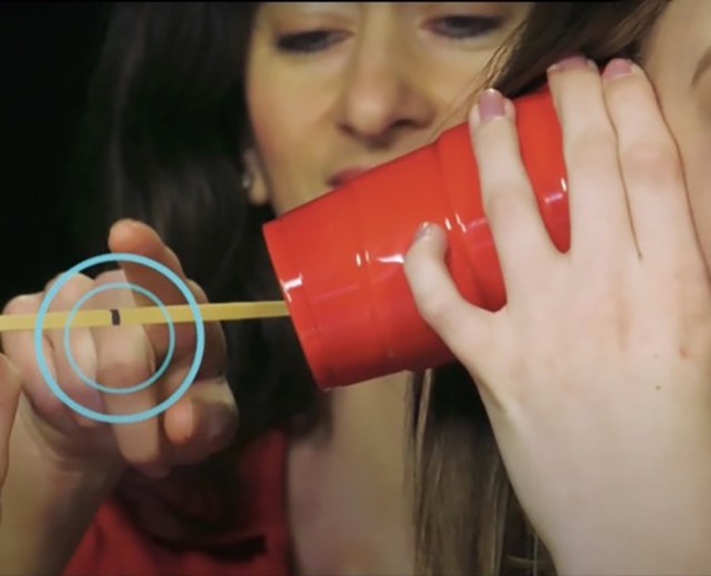 A NASA employee demonstrating when you touch the rubberband that is attached to the red cup, it will make a sound.