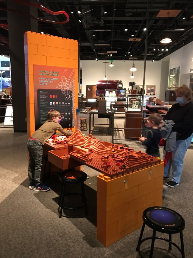 A child building habitats on a simluated Martian terrain at a museum