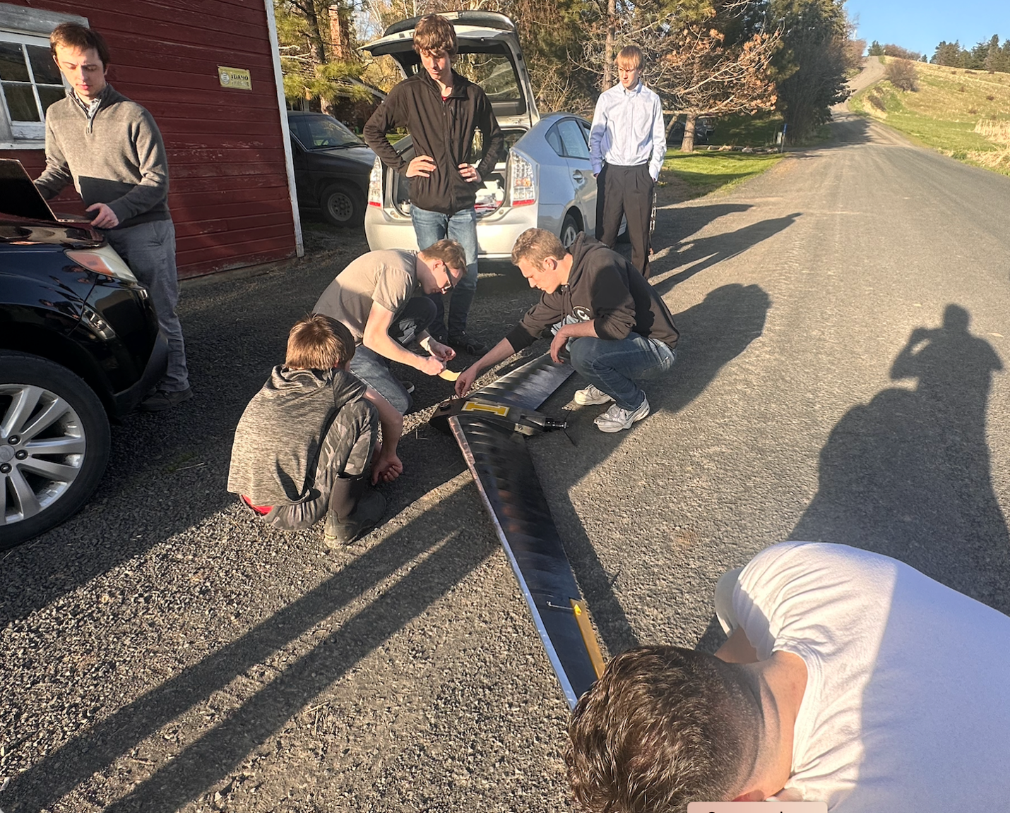 A group of students look on while another group of student work on an airplane.