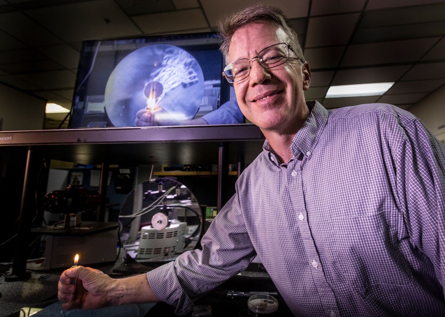 Tom Moss, software team lead in the Applied Physics Laboratory, demonstrates the Schlieren effect with a lighter inside the Applied Physics Lab at Kennedy Space Center.