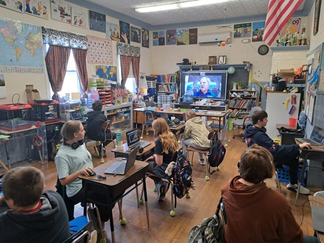 Photo of children in a classroom with an astronaut on a television screen