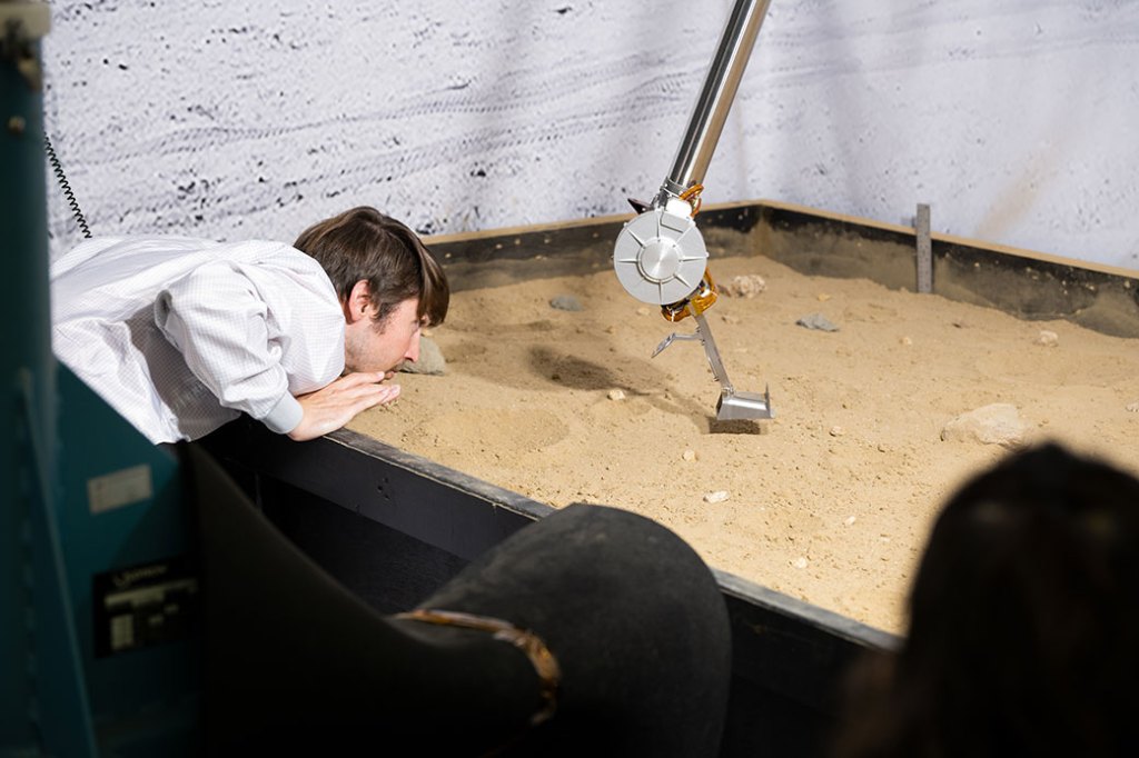 A man surveys testing of a prototype of a robotic arm, technology that will be used for lunar exploration missions