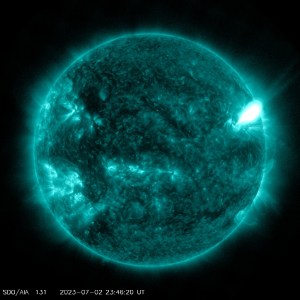 A golden Sun, with bright active regions scattered across it. In the upper right area of the Sun, a bright burst of solar material shoots off the Sun.