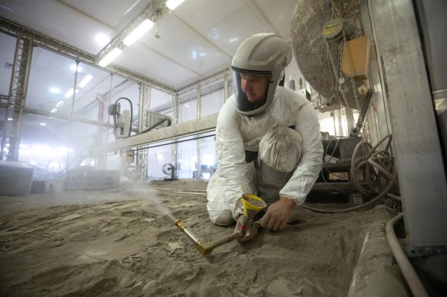 A man testing small- and medium-sized bucket drums in the Granular Mechanics and Regolith Operations Lab’s “big bin” during prototype development for the pilot excavator, a robotic mission designed for lunar operations.