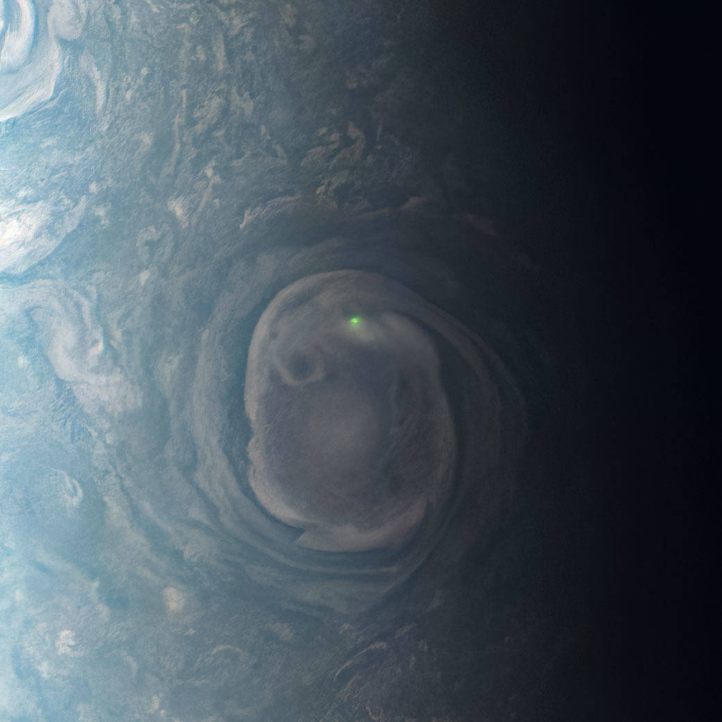 In this view of a vortex near Jupiter’s north pole, NASA’s Juno mission observed the glow from a bolt of lightning.