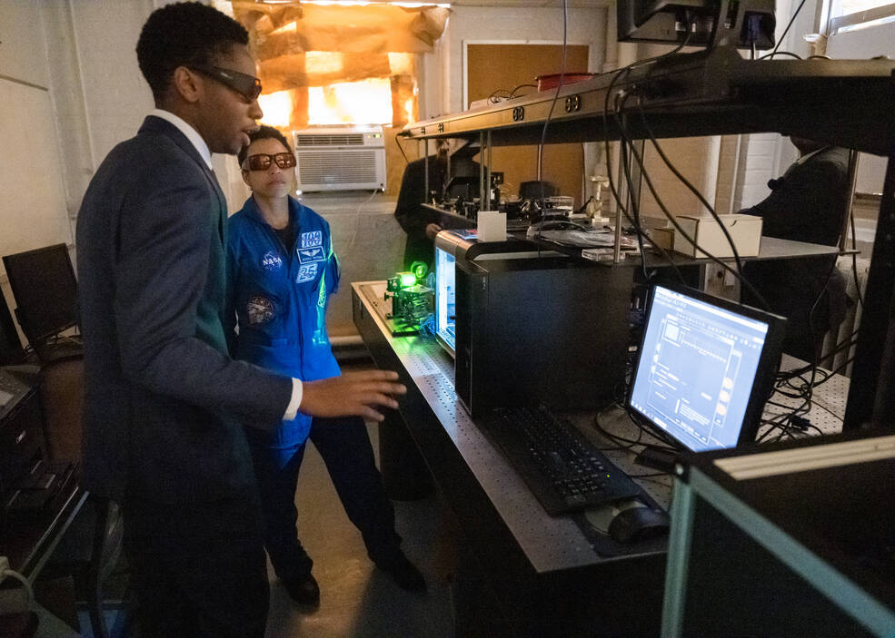 Howard University student Miles Phillips gives NASA astronaut Jessica Watkins a demonstration of his work with lasers during a tour.